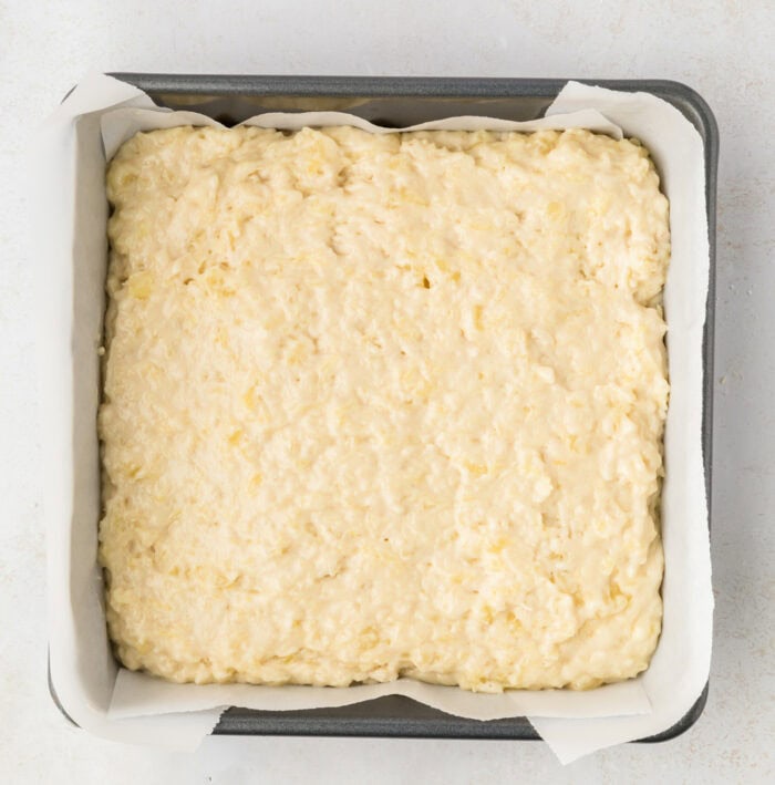 Pineapple cake batter in a square baking pan