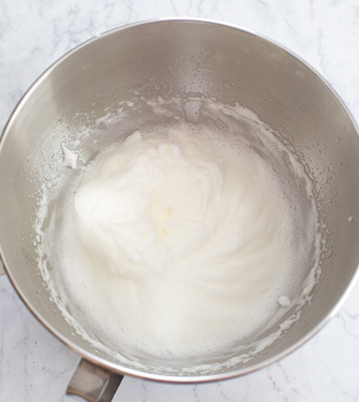 Egg whites in stiff peaks in a mixing bowl