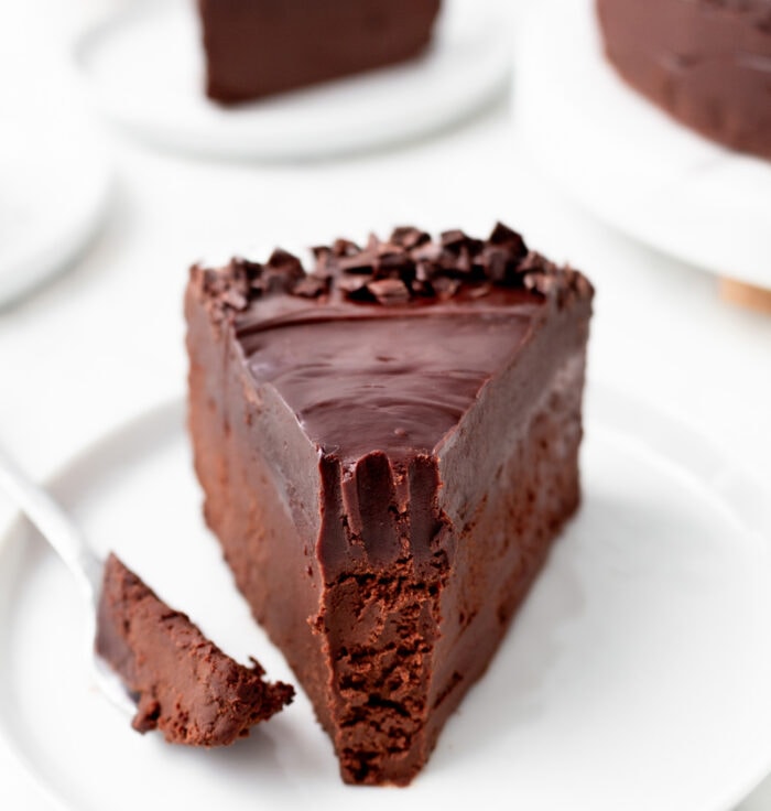 A bite taken from a slice of chocolate cake