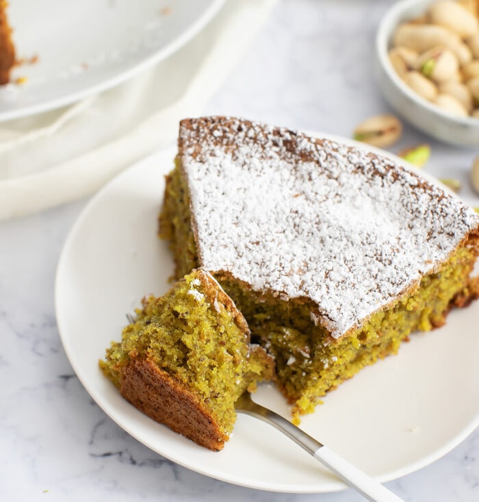 A slice of pistachio cake dusted with powdered sugar