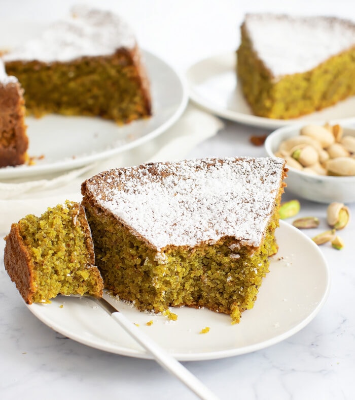 A bite taken from a slice of pistachio cake