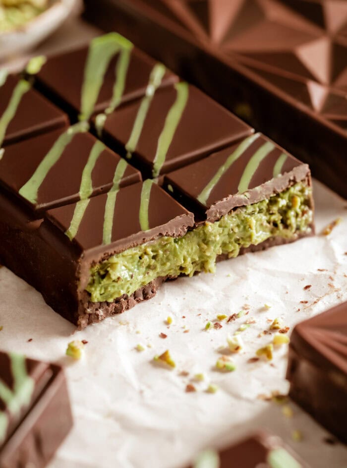 Close-up of a sliced Dubai chocolate bar showing the layered dark chocolate shell and vibrant green pistachio-kataifi filling.