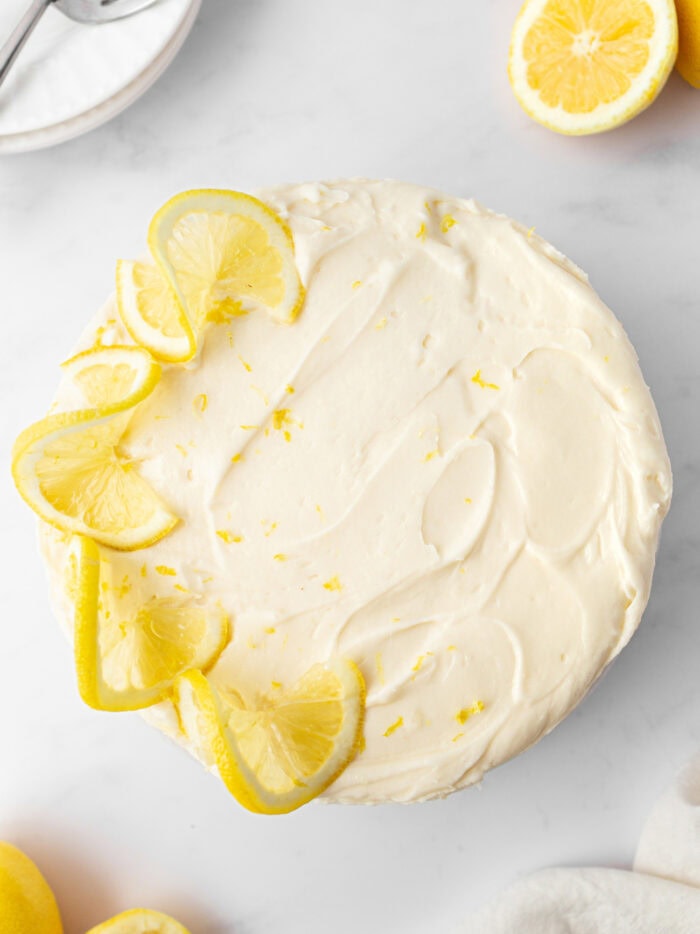 A lemon cake decorated with frosting and fresh lemon slices