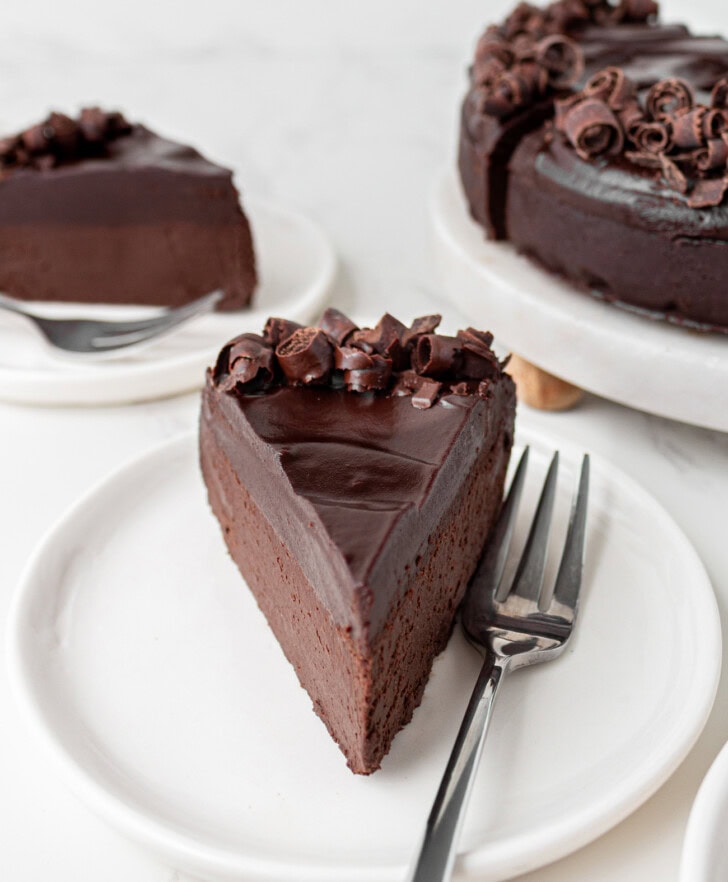 A slice of chocolate cake on a white plate with a fork