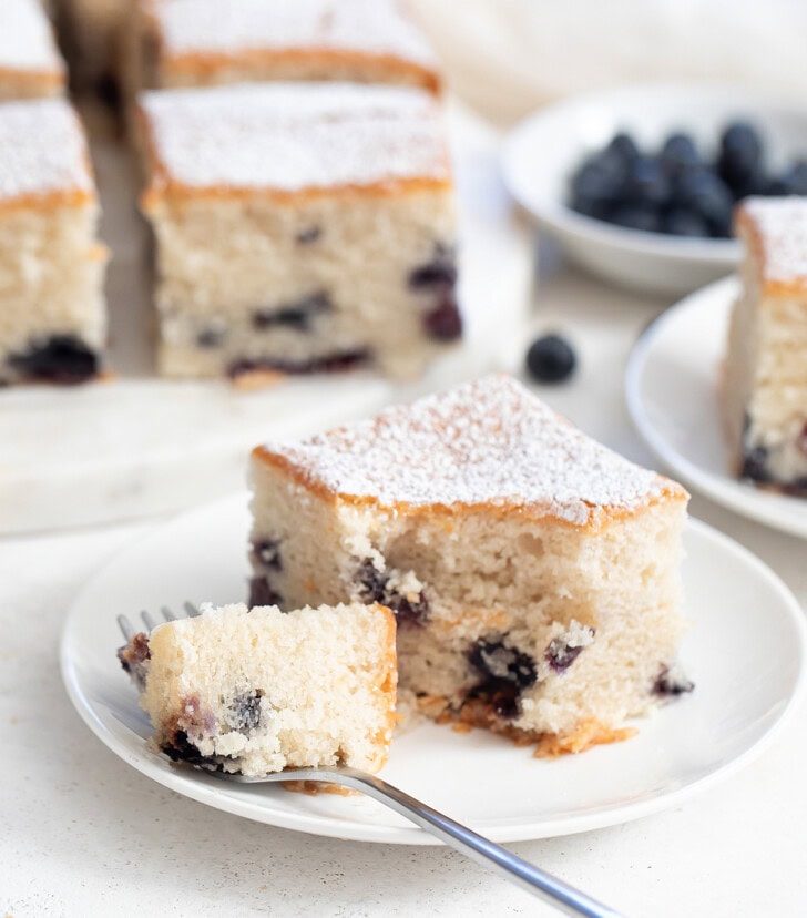A bite of a slice of blueberry cake on a fork