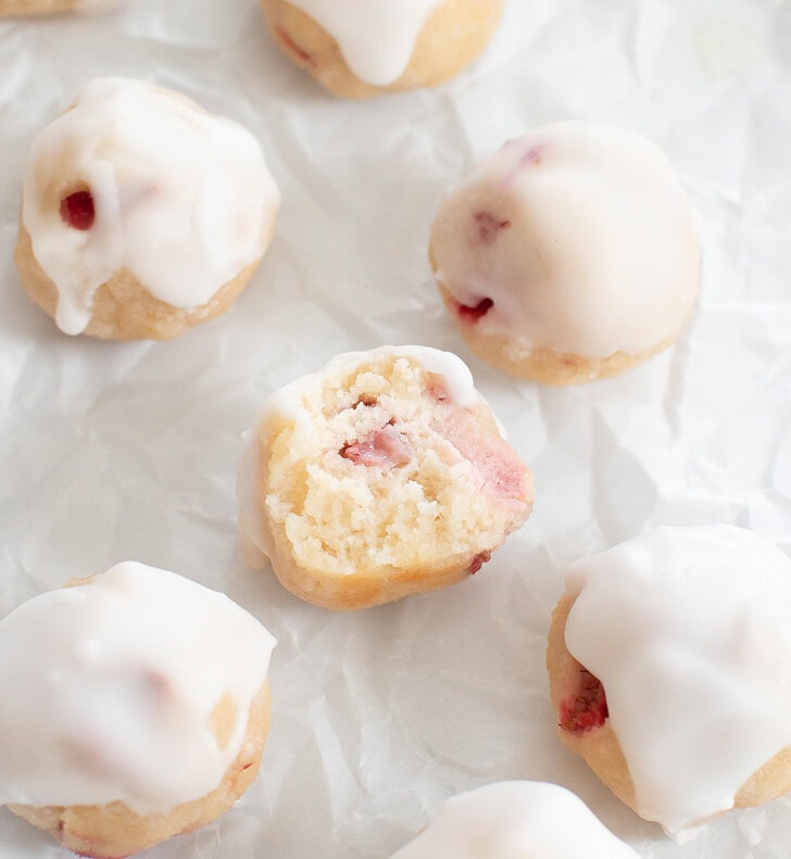 A bite taken from a strawberry donut hole