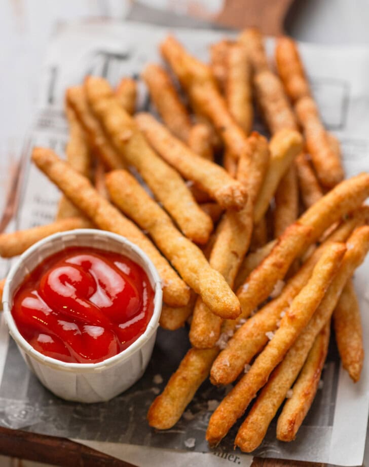 A pile of fries with salt and a side of ketchup