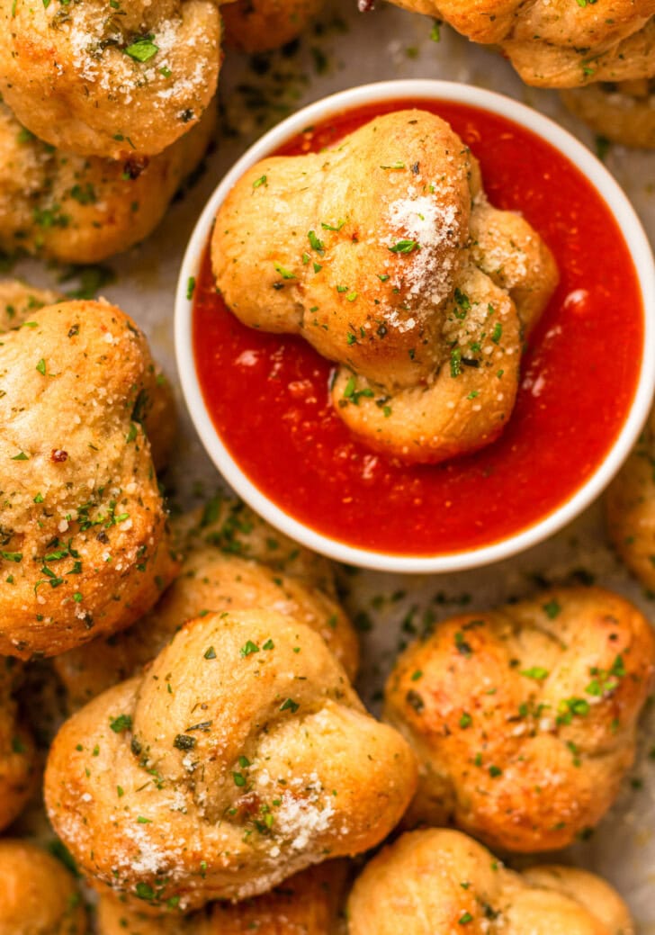 A garlic knot dipped in marinara sauce