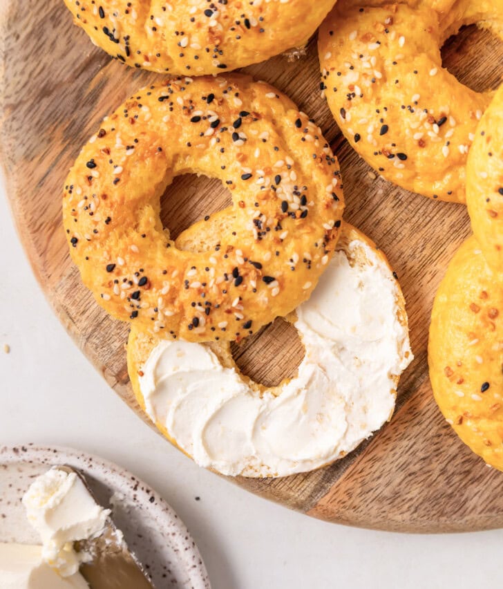 A bagel cut in half with cream cheese on half