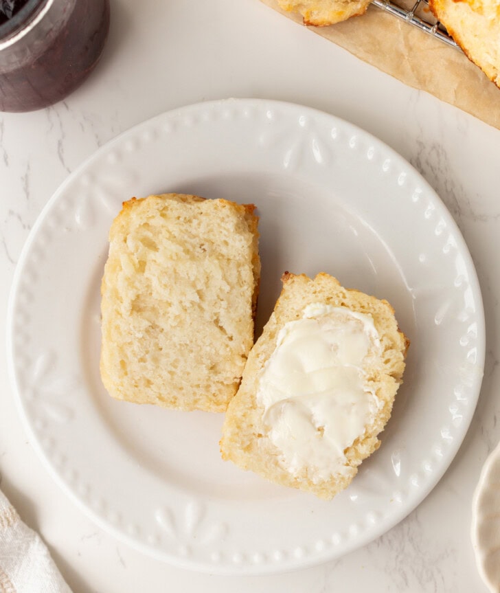 A biscuit cut in half with butter spread on one half
