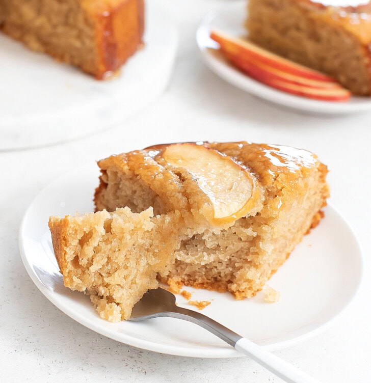 A bite taken from a slice of apple cake on a fork