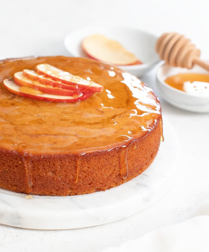An apple cake garnished with thin apple slices and honey