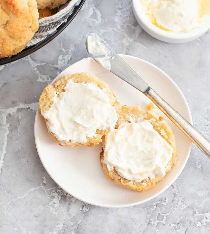 A biscuit cut in half with butter spread on it