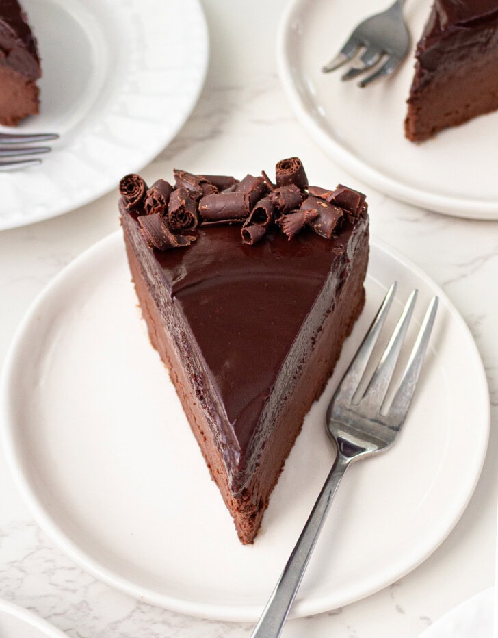 A slice of chocolate cake on a white plate with a fork