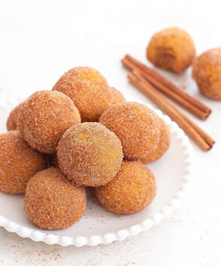 A pile of pumpkin donuts on a small white plate