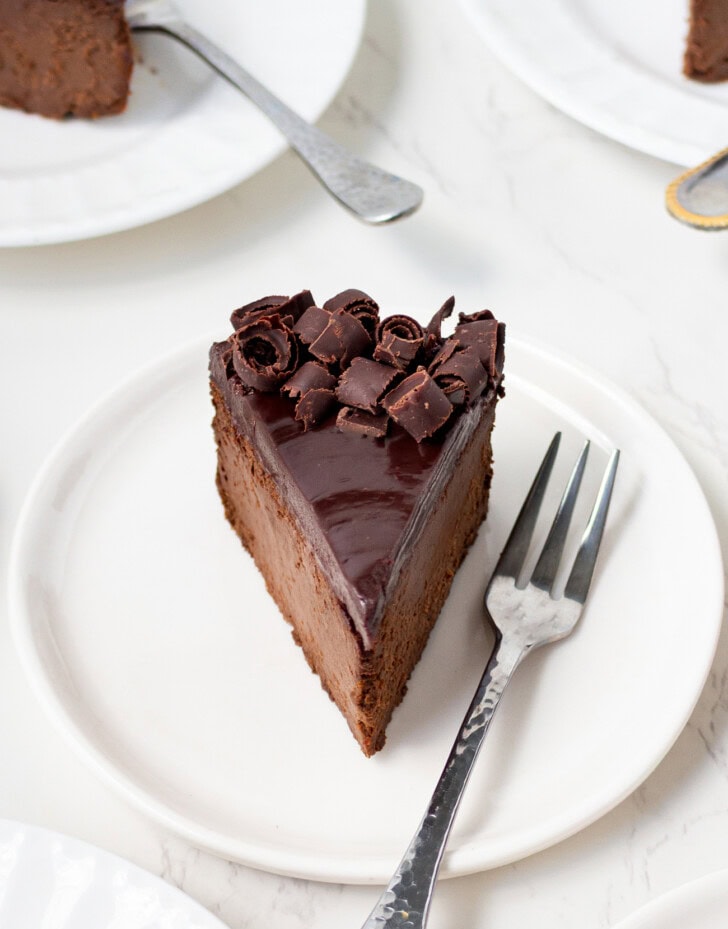 A slice of chocolate cake on a small white plate with a fork