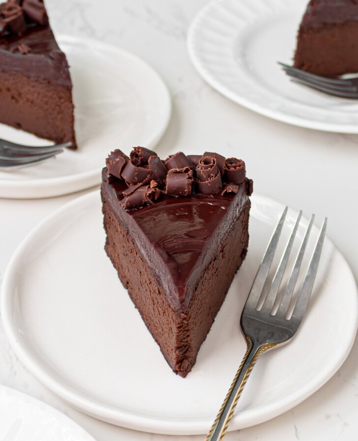A slice of chocolate cake on a white plate with a fork