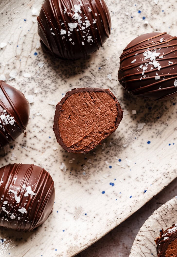 Cottage cheese truffles dipped in chocolate with a chocolate drizzle and salt sprinkled on top