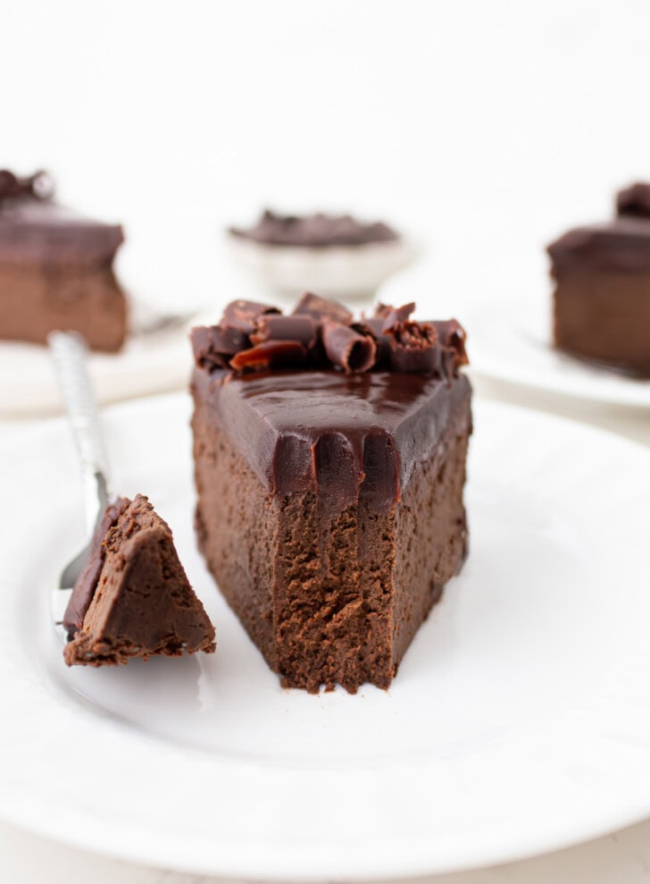 A bite of chocolate cake on a fork next to the slice of cake