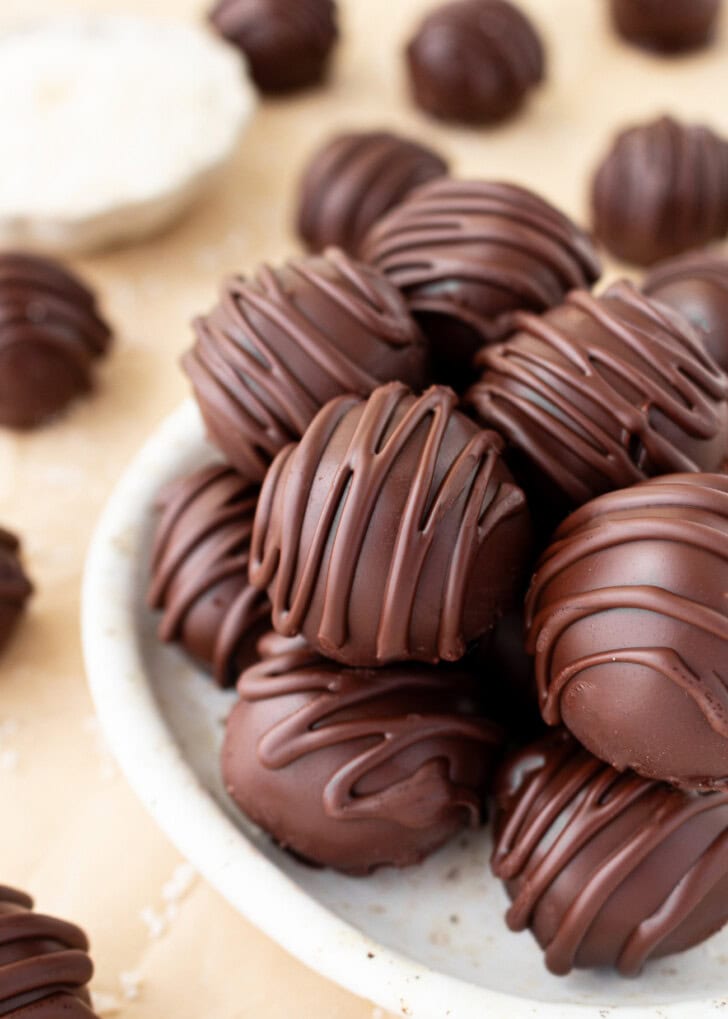 Multiple chocolate-covered keto coconut truffles in a small bowl
