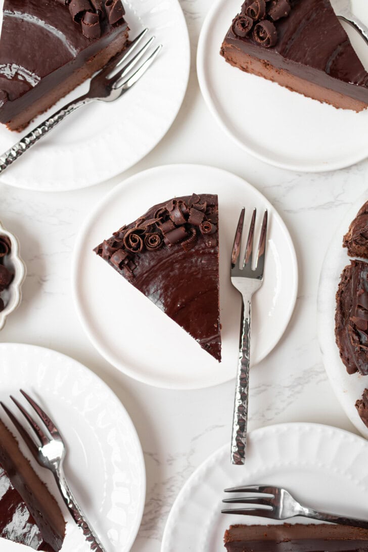 Slices of chocolate cake on white plates with forks