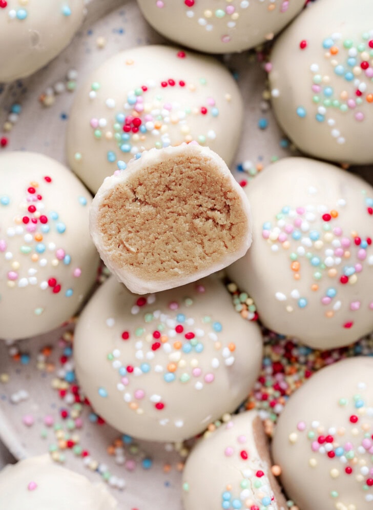Close-up of a cake ball cut in half coated in white chocolate with sprinkles