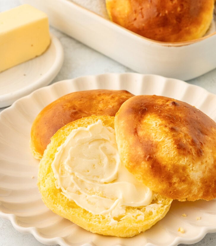 A bread roll cut in half with butter spread on one half