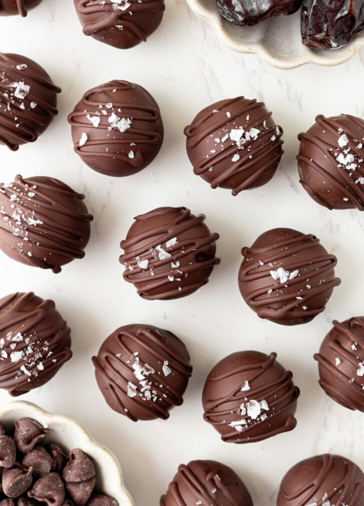 No bake brownie balls dipped in chocolate with a chocolate drizzle and flaky salt on top