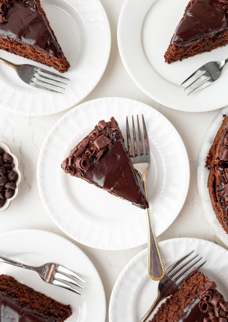 Slices of chocolate cake with chocolate frosting on plates with forks
