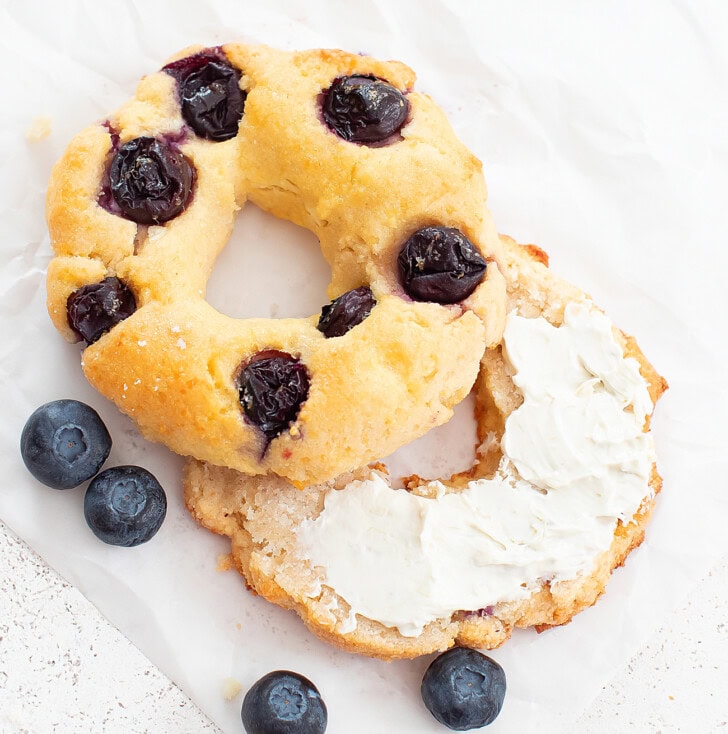 A blueberry bagel cut in half with cream cheese spread