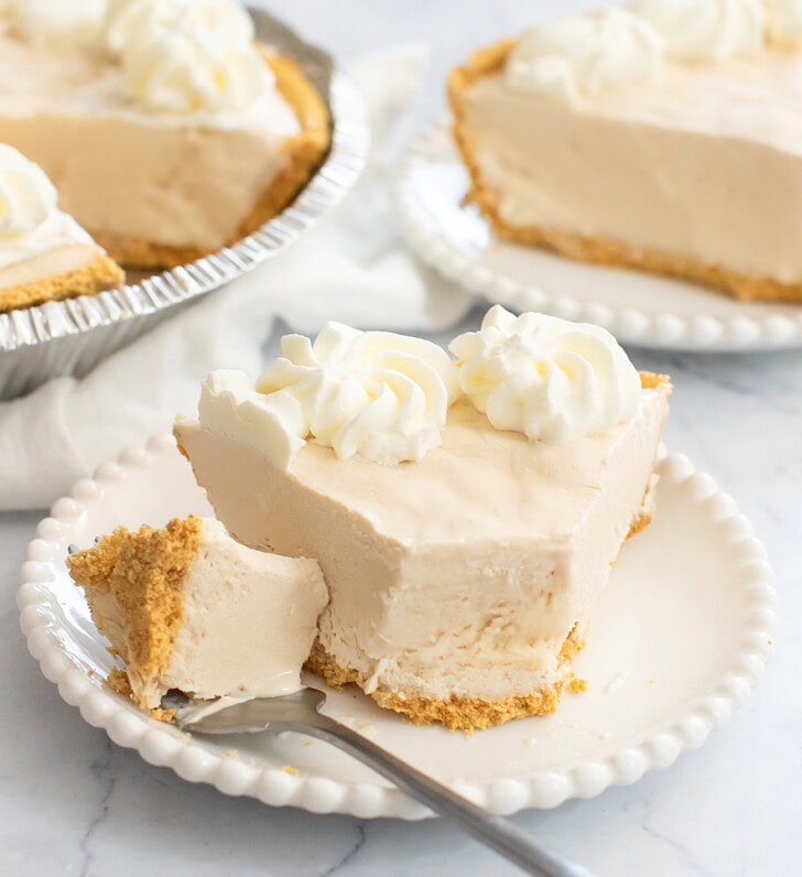 A slice of cottage cheesecake on a plate with a bite on a fork