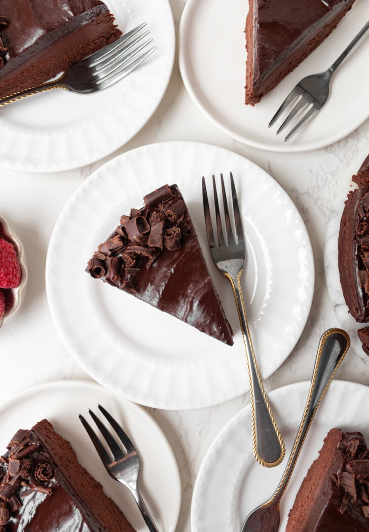 Slices of chocolate cake on white plates with forks