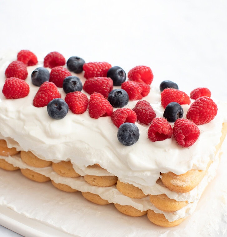 A cottage cheese cake topped with whipped cream frosting and fresh berries