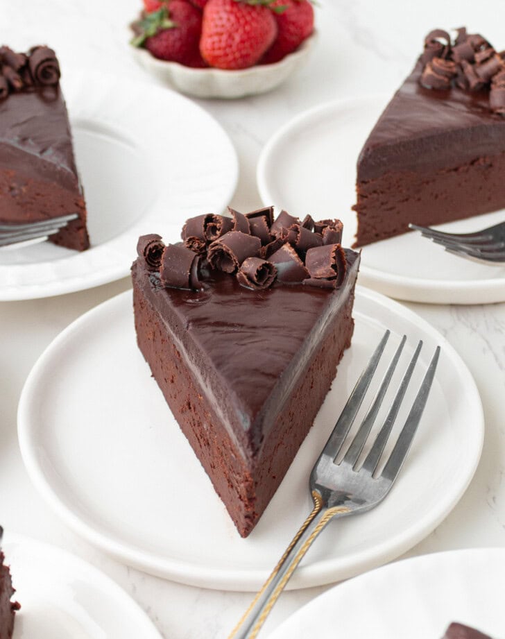 A slice of chocolate cake on a white plate with a fork