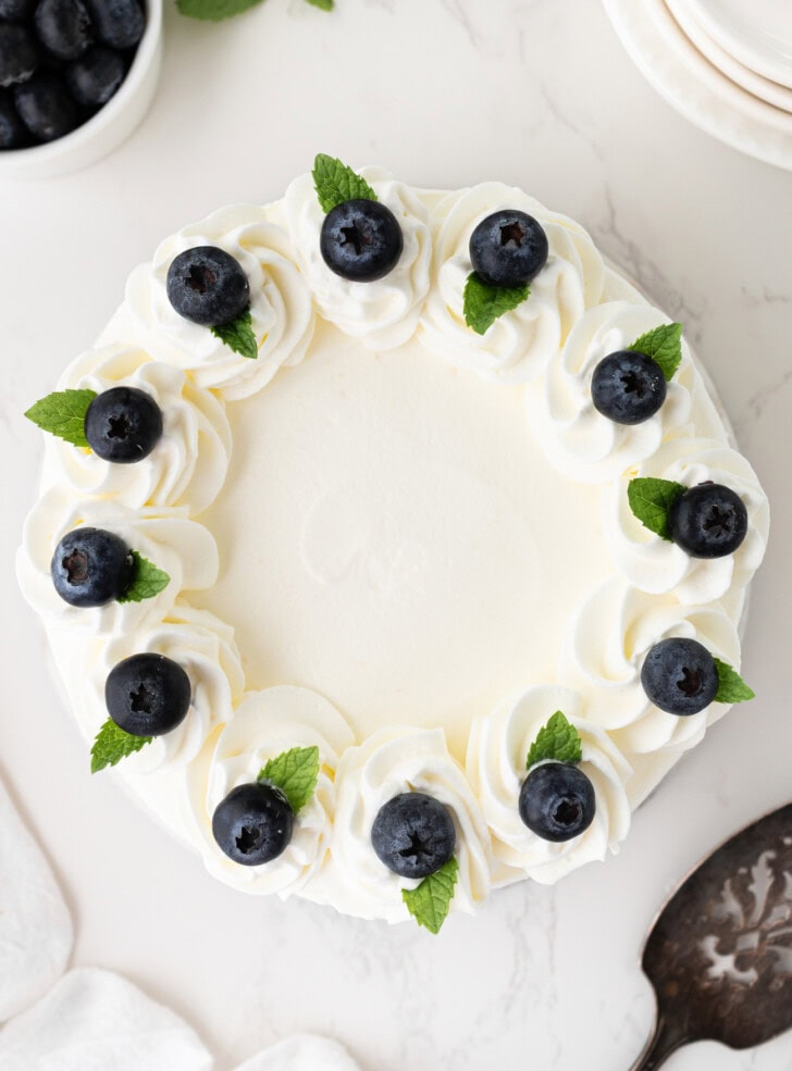 A cheesecake decorated with whipped cream frosting and fresh blueberries