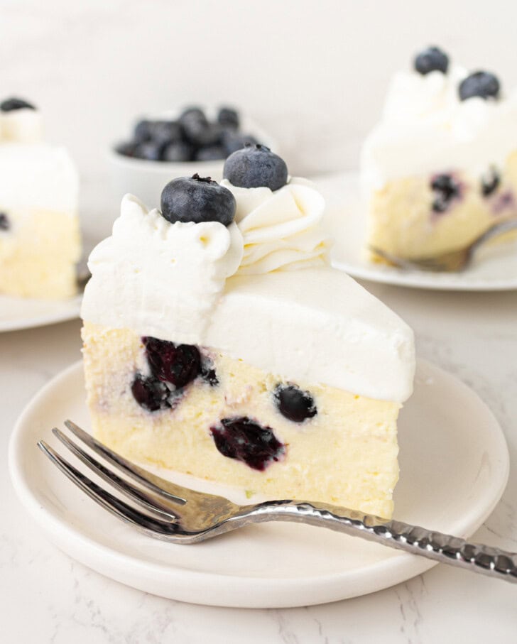 A slice of blueberry yogurt cheesecake on a plate with a fork