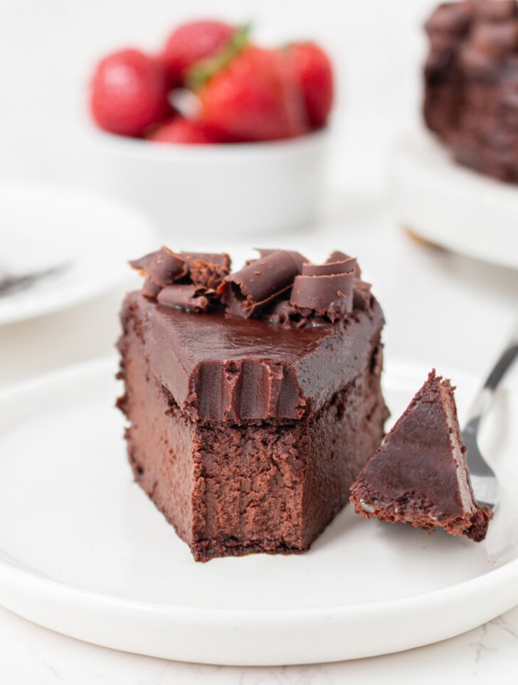 A bite of chocolate cake on a fork next to a slice of cake