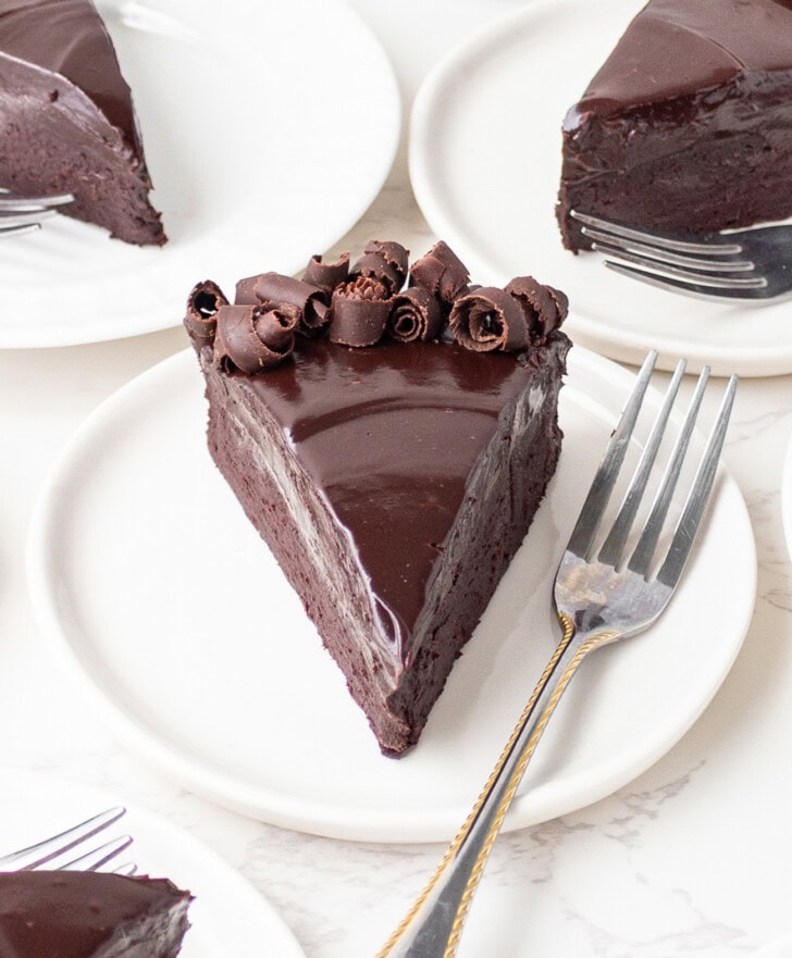 A slice of chocolate cake on a white plate with a fork