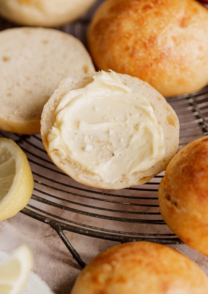 A lemon bread roll cut in half with butter spread on one half