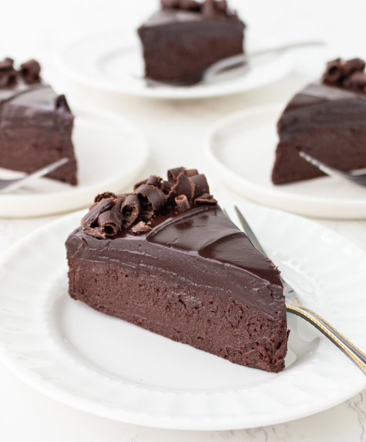 A slice of chocolate cake on a white plate with a fork