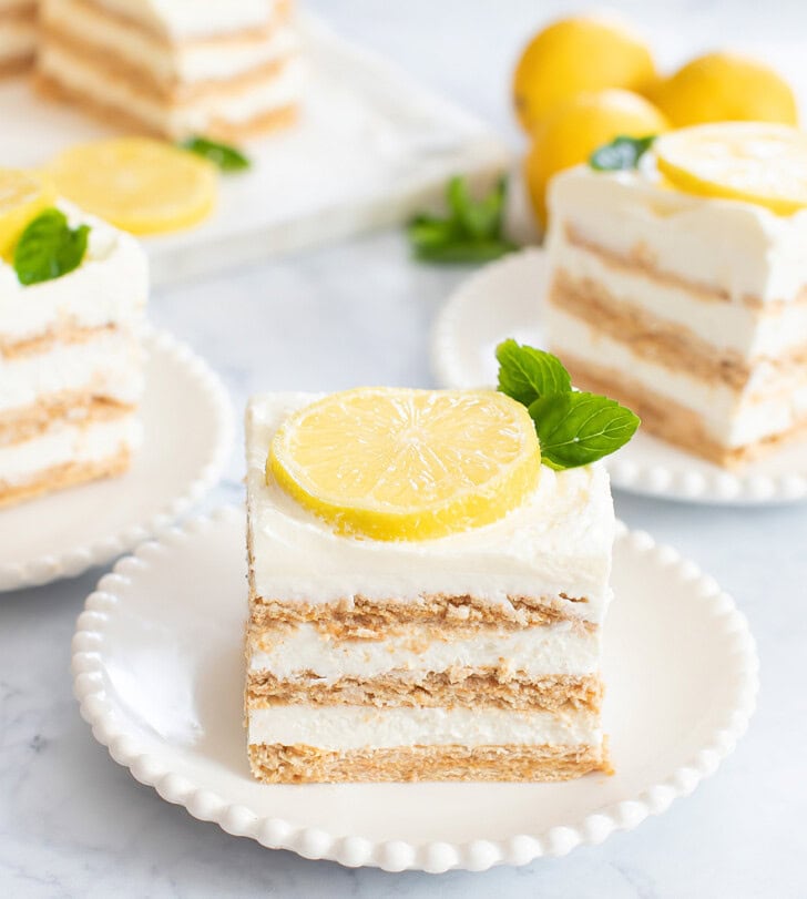 Pieces of no bake lemon yogurt cheesecake with lemon slices and herbs on top