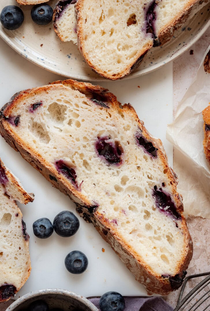 A slice of blueberry bread with fresh blueberries