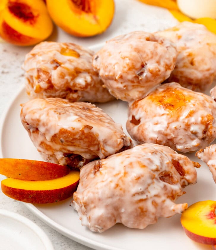 Peach fritters on a plate with slices of fresh peaches