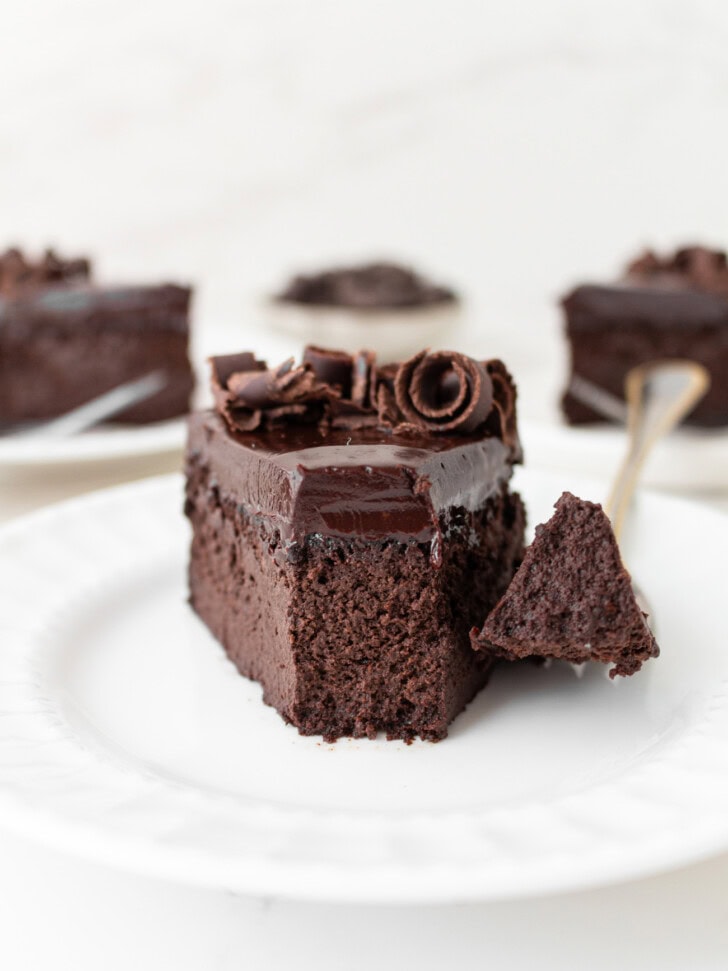 A bite of cake on a fork taken from a slice of chocolate cake