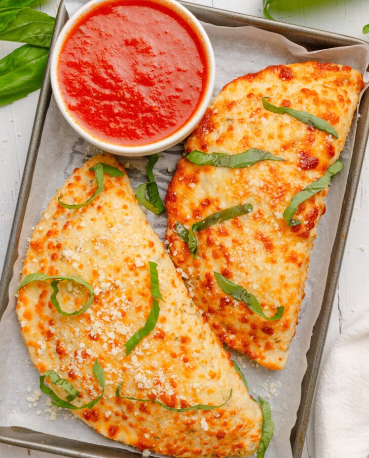Two calzones with a dipping sauce