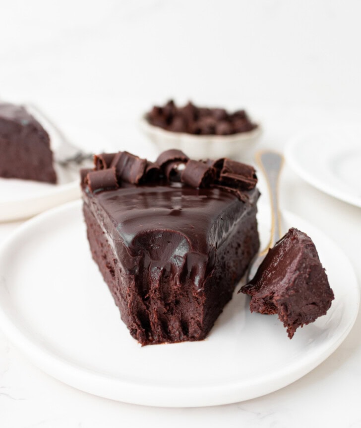 A bite of cake on a fork next to a slice of chocolate cake