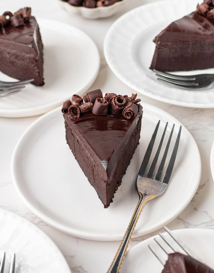 A slice of chocolate cake with a fork on a small white plate