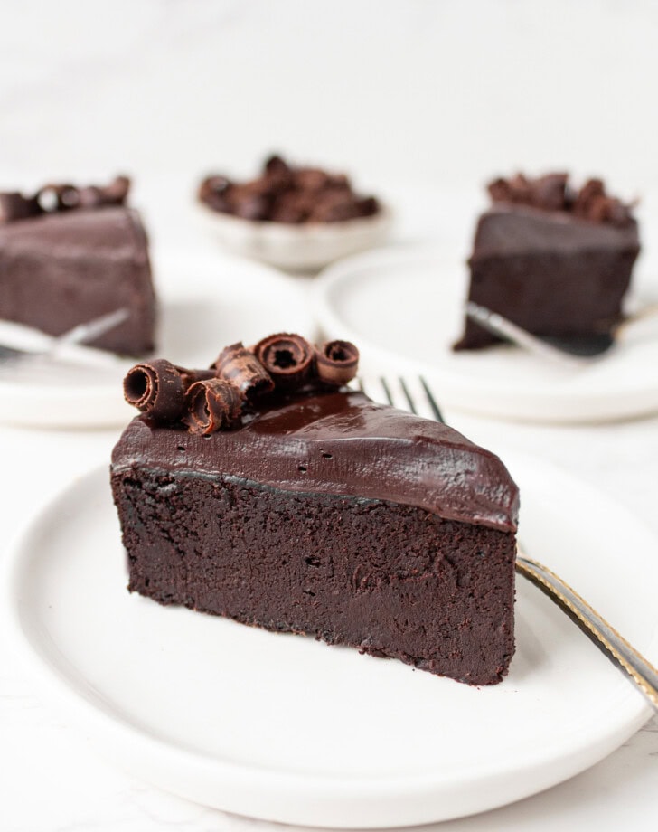 A slice of fudgy chocolate cake on a small white plate
