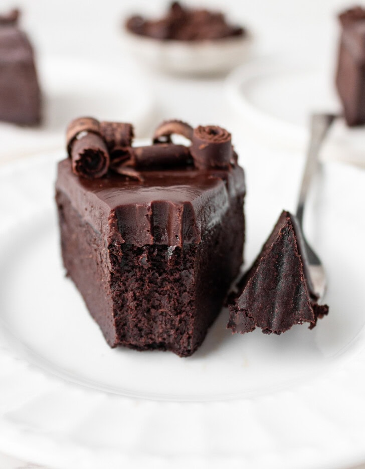 A bite of cake on a fork taken from a slice of chocolate cake