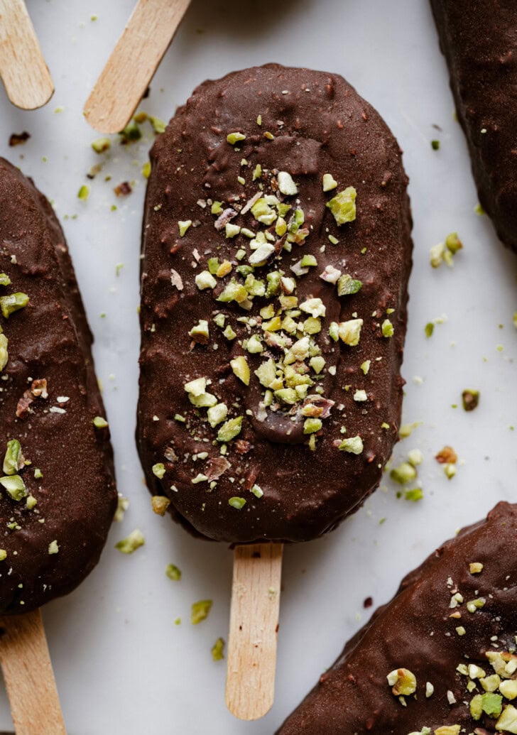 Ice cream bars dipped in dark chocolate with crushed pistachios on top